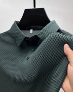 Dark green textured polo shirt close-up, showing collar, placket buttons and woven fabric texture on shoulder