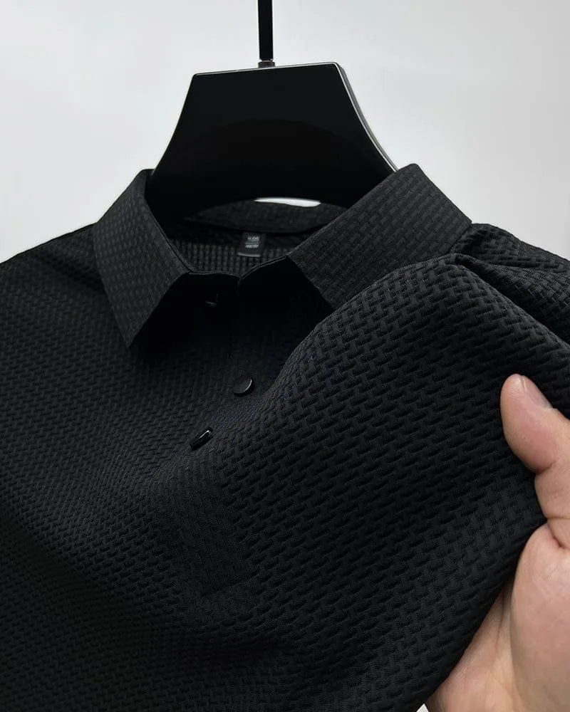 Black textured polo shirt detail, showing collar, button placket and woven fabric texture on sleeve