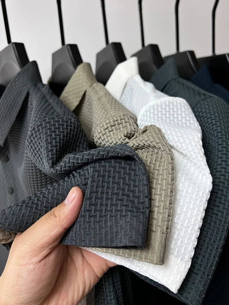Hand holding folded sleeve showing woven texture across six colourways on hangers, close-up of fabric detail