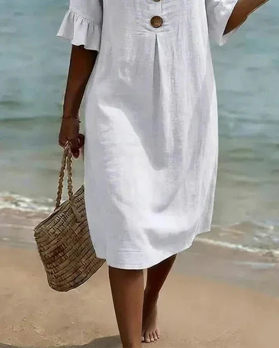 Rear view of white knee-length shift dress showing relaxed silhouette while walking along the shoreline