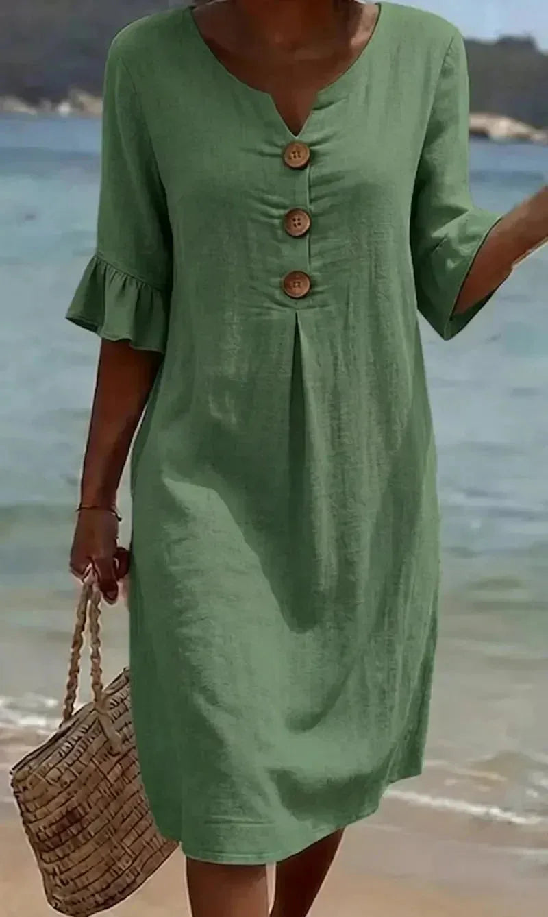 Front close-up of sage green textured button dress with ruffle sleeve detail worn near the water