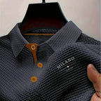 Grey textured polo shirt close-up showing woven fabric pattern and tan placket trim on collar