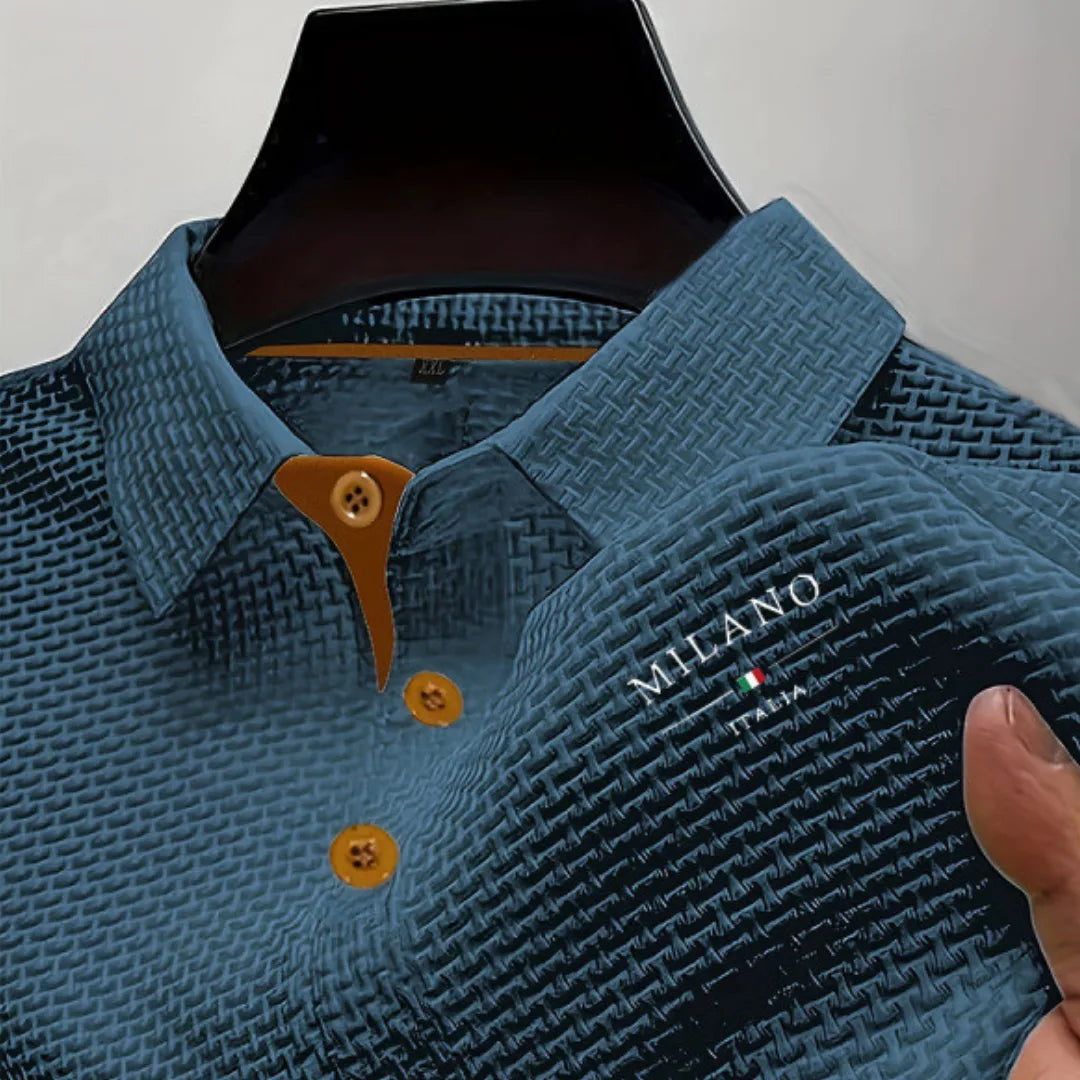 Teal blue textured polo shirt held by hand, showing fabric weave texture and embroidered logo on chest
