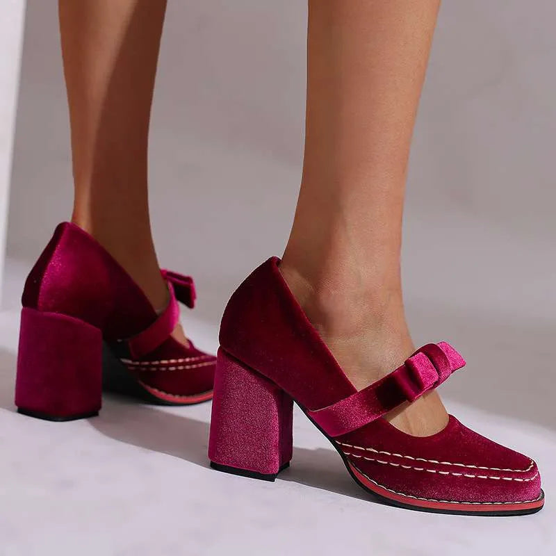 Burgundy velvet mary jane heels against a plain backdrop, showing block heel and red sole trim