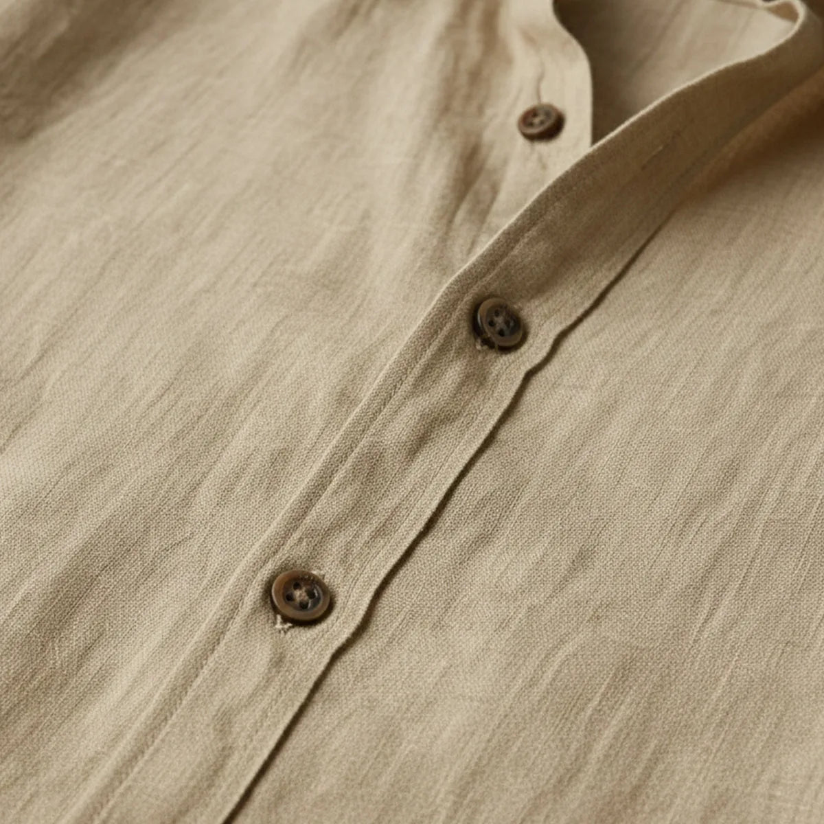 Close-up of brown buttons and placket stitching on the khaki linen shirt