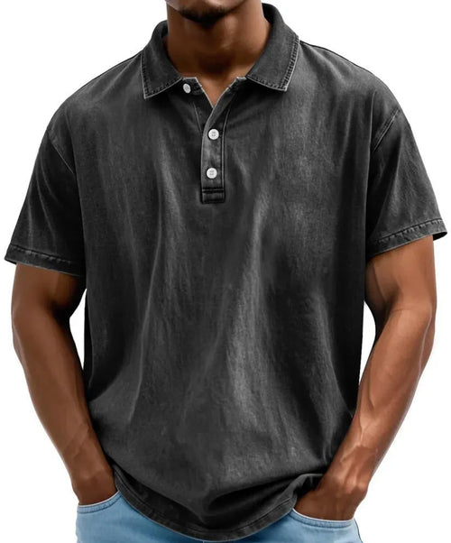 Front view of man wearing a black acid-washed polo shirt with button placket and collar, short sleeves