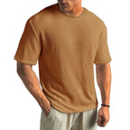 Close front view of a man in a rust brown textured waffle-knit crew neck t-shirt paired with linen trousers