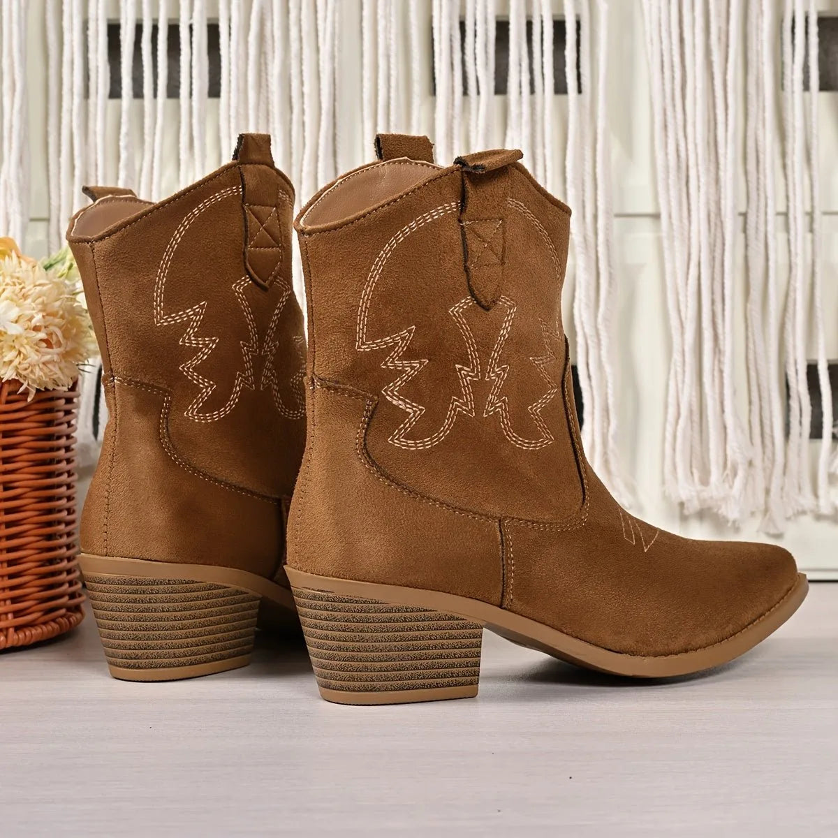 Back view of two light brown suede western ankle boots showing heel pull tabs and stitched detailing side by side
