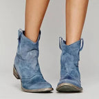 Black suede western-style ankle boots viewed from the front, showing the pointed toe and side pull tabs.
