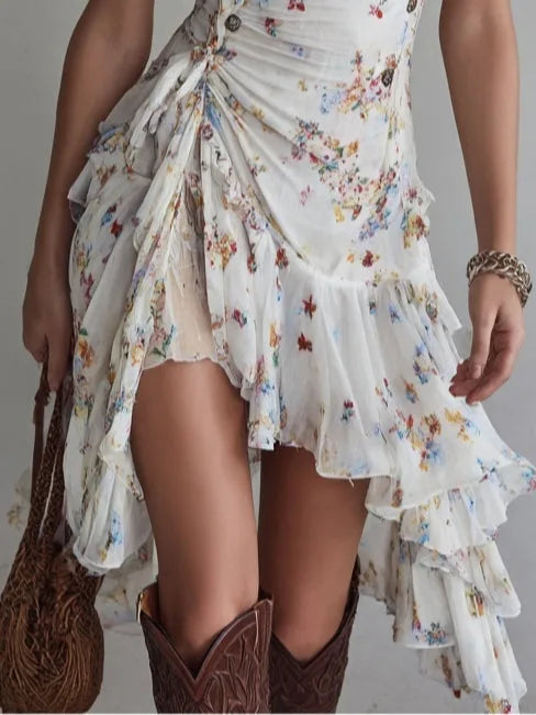 Close-up of the asymmetric ruffled skirt and tiered hemline, styled with brown leather cowboy boots and a woven shoulder bag