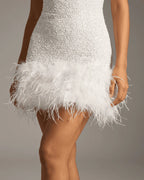 Detail shot of the sequin skirt meeting the soft white feather hem at mid-thigh length
