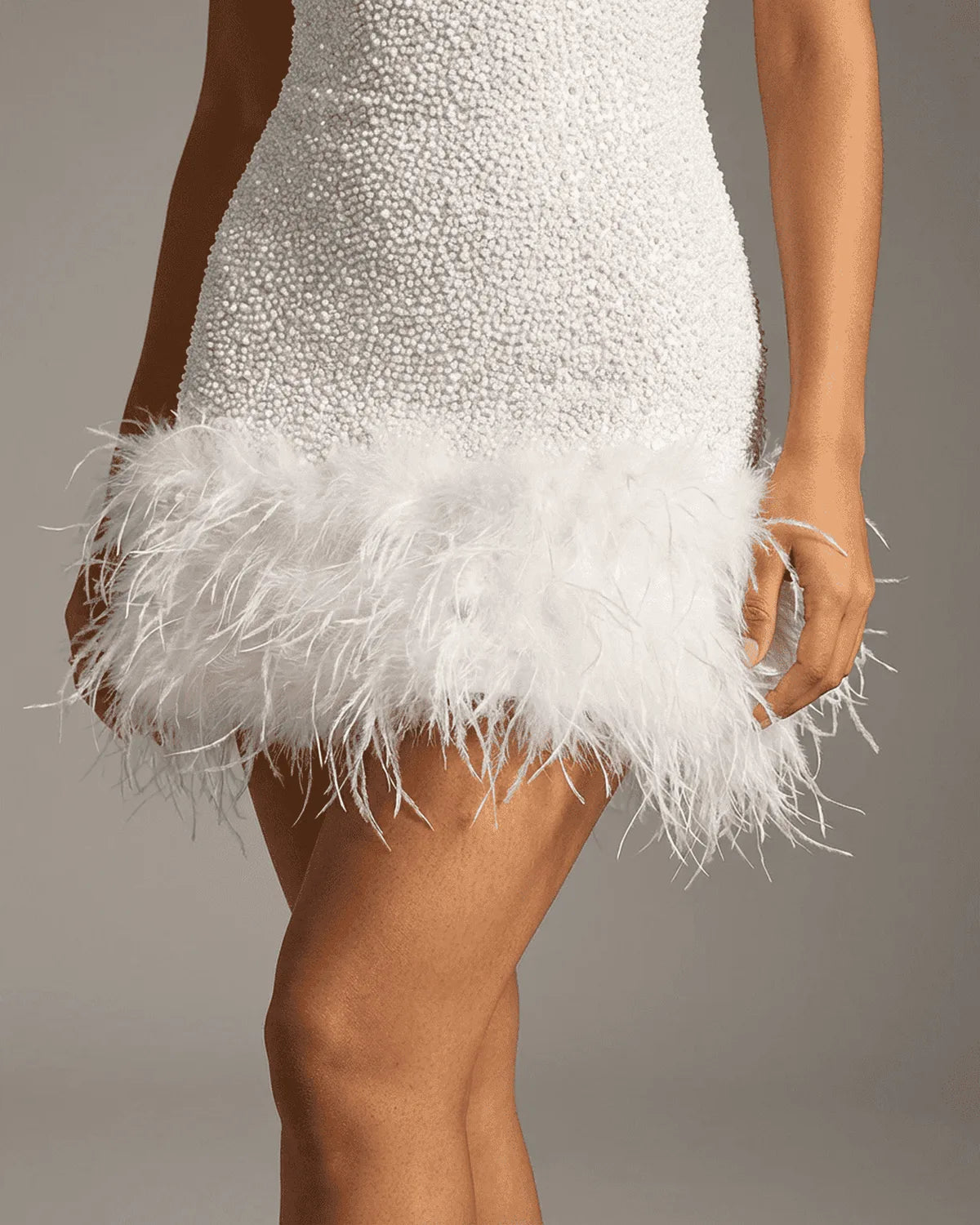 Detail shot of the sequin skirt meeting the soft white feather hem at mid-thigh length