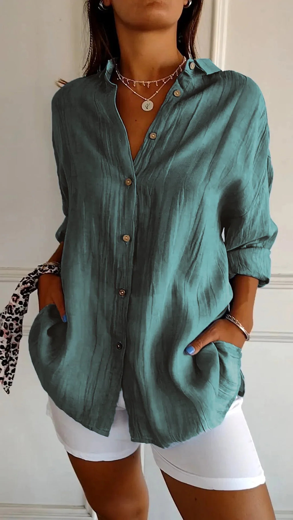 Teal green linen shirt buttoned up with textured crinkled fabric visible, worn with layered necklaces