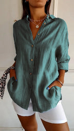 Teal green linen shirt buttoned up with textured crinkled fabric visible, worn with layered necklaces