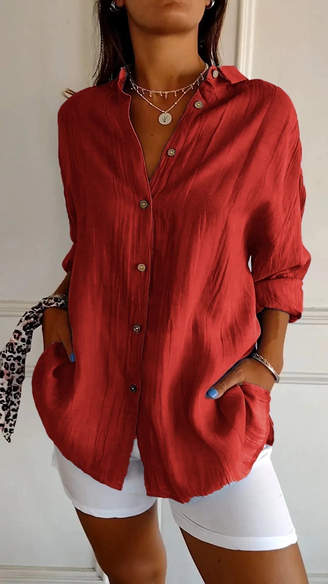 Rust red linen shirt with horn buttons and rolled sleeves, hand tucked into the hip pocket