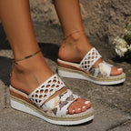 Top-down view of leopard print wedge sandals with gold woven straps and jute platform trim on concrete pavement
