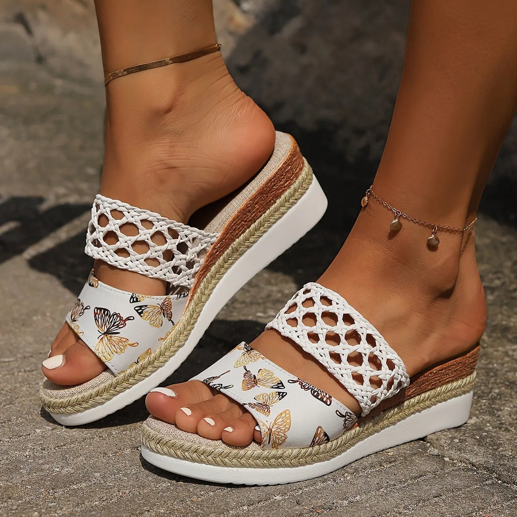White woven lattice strap sandal with golden butterfly print vamp, shown on bare feet with espadrille trim platform
