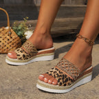 Angled close-up of leopard print sandal with gold woven ankle strap, worn with a gold chain anklet